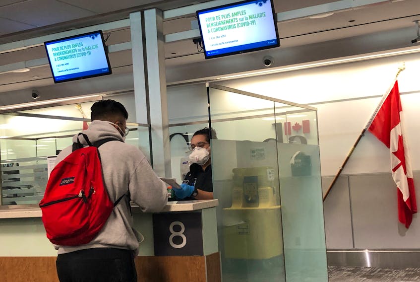 A Canada Border Services Agency (CBSA) officer wears a protective face mask amid coronavirus fears as she checks passports for those arriving at Toronto Pearson International Airport on Sunday, March 15.