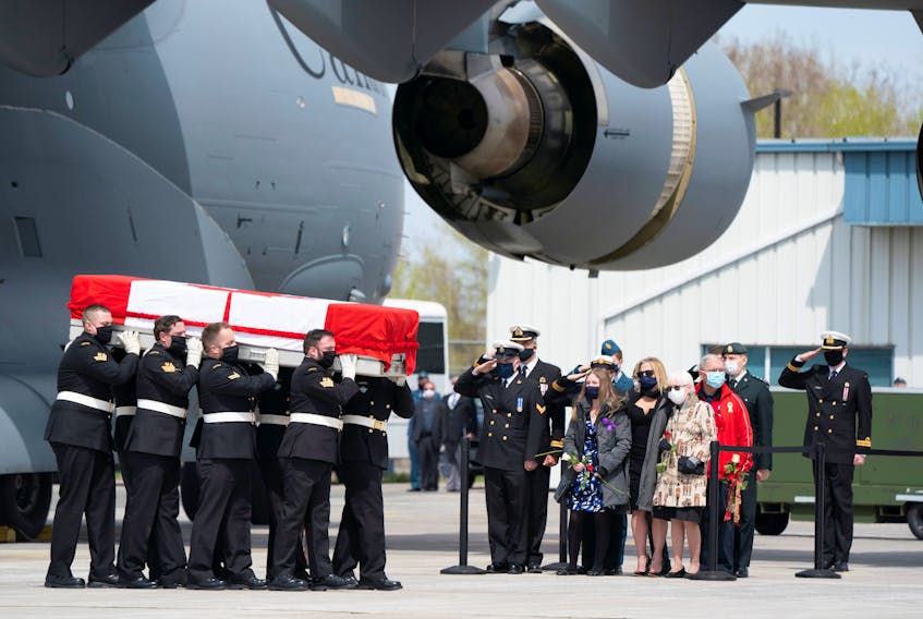 Family members watch as masked pallbearers carry the casket of Sub-Lt. Abbigail Cowbrough to a hearse during a repatriation ceremony for the six Canadian Armed Forces members killed in a helicopter crash in the Mediterranean, at CFB Trenton, Ontario, on Wednesday, May 6, 2020.