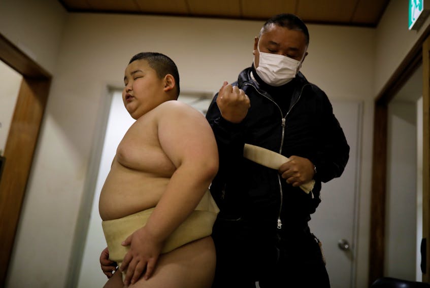 Taisuke Kumagai adjusts his son Kyuta's loincloth called a mawashi, during a training session at Komatsuryu sumo club in Tokyo, Japan, Dec. 6, 2020.