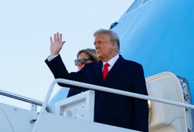 U.S. President Donald Trump, accompanied by first lady Melania Trump, waves as he boards Air Force One at Joint Base Andrews in Maryland on Jan. 20, 2021.