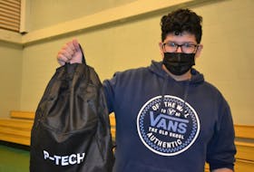 Grade 11 student Kaisa'n Stevens holds up his P-Tech branded backpack from IBM Canada at the announcement of the Unama'ki P-Tech school at Allison Bernard Memorial High School on Tuesday. Stevens said he enrolled in the program because he's interested in engineering and hopes to be a nuclear engineer in the future. ARDELLE REYNOLDS/CAPE BRETON POST