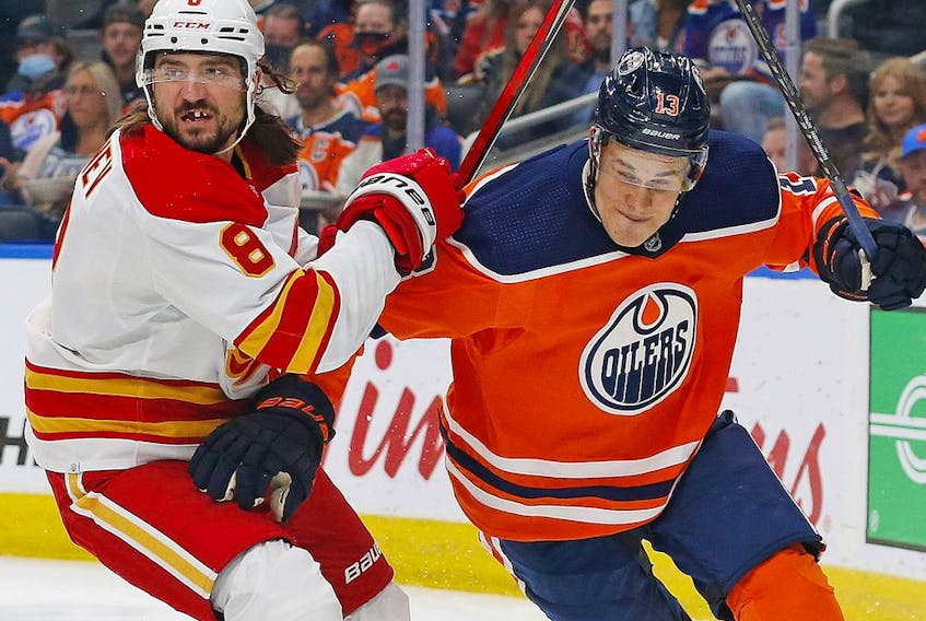 Calgary Flames defencemen Chris Tanev and Edmonton Oilers forward Jesse Puljujarvi battle for a loose puck during pre-season action at Rogers Place in Edmonton on Oct. 4, 2021.