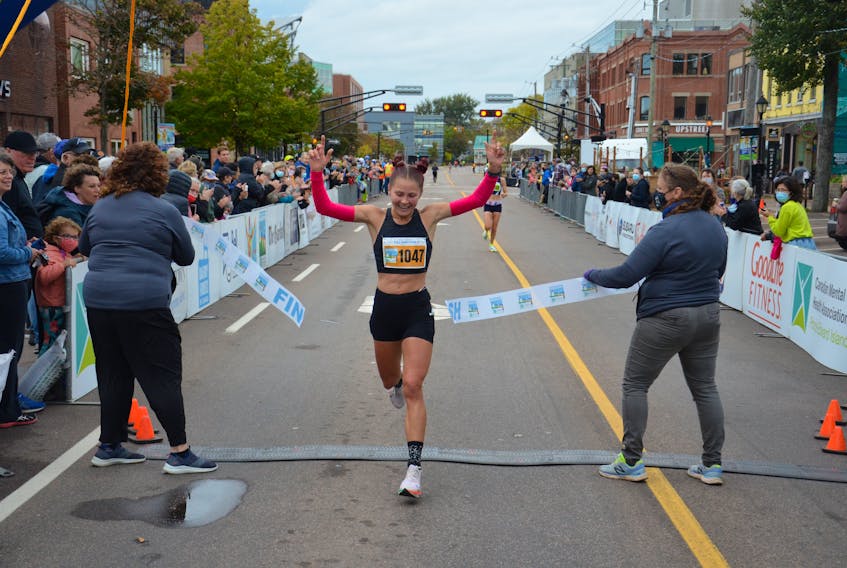 Rachel Barich raises her arms in the air as she crosses the finish line In the Prince Edward Island Marathon on Oct. 16. Barich, the top female runner in the 42.2-kilometre full marathon, had a time of two hours 56 minutes 55 seconds (2:56:55).