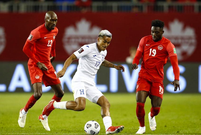 Andy Najar (No. 17) of Honduras dribbles the ball as Atiba Hutchinson (No. 13) and Alphonso Davies (No. 19) of Canada defend during a 2022 World Cup Qualifying match at BMO Field on September 2, 2021 in Toronto.