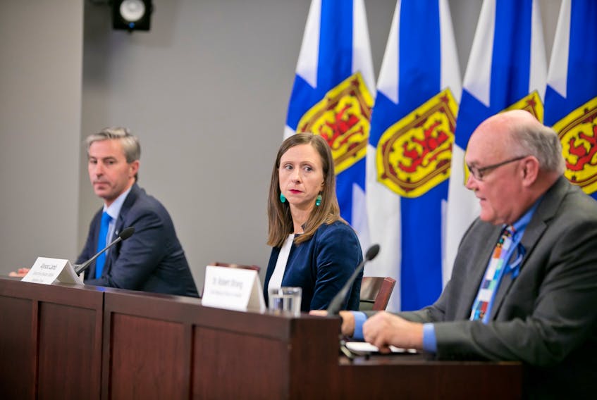 Nova Scotia Premier Tim Houston and Alyson Lamb, executive director of Nova Scotia Health's western zone, listen as Dr. Robert Strang, the province's chief medical officer of health, speaks at a COVID-19 briefing in Halifax on Tuesday, Oct. 19, 2021.