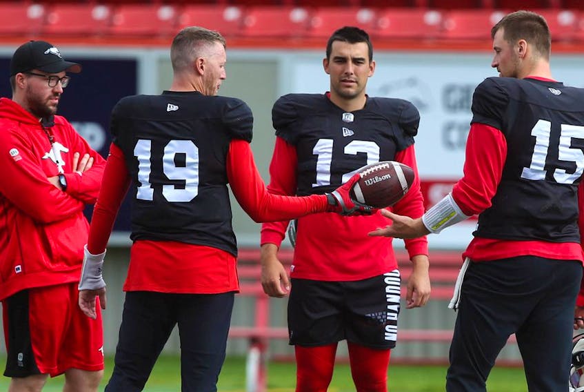 Stampeders quarterbacks (from left) Bo Levi Mitchell, Jake Maier and Michael O’Connor chat with a coach during practice at McMahon Stadium in Calgary on Thursday, Sept. 30, 2021. 