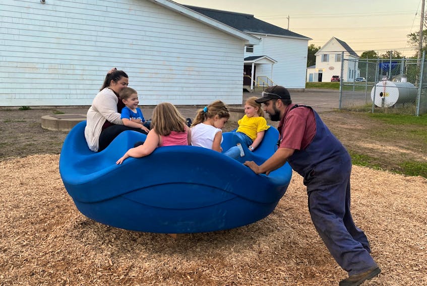 Katie Devine, with children Parker and Penny, as well Avery and Audrey Johnson (backs to picture), enjoying the inclusive spinner, being spun by Kyle Slack. The installation of the equipment is part of the Debert Elementary School Parent Teacher Association (PTA) Playground Initiative. Devine and Slack are PTA members.