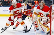 Calgary Flames defencemen Erik Gudbranson battles with Edmonton Oilers forward Zach Hyman in front of Flames goaltender Jacob Markstrom during a pre-season game at Rogers Place in Edmonton on Oct. 4, 2021.