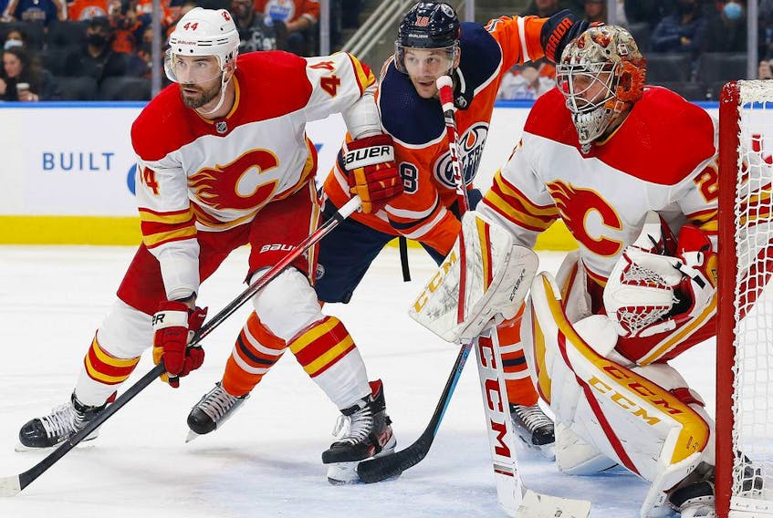 Calgary Flames defencemen Erik Gudbranson battles with Edmonton Oilers forward Zach Hyman in front of Flames goaltender Jacob Markstrom during a pre-season game at Rogers Place in Edmonton on Oct. 4, 2021.