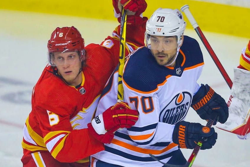 The Calgary Flames’ Juuso Valimaki battles the Edmonton Oilers’ Colton Sceviour during a pre-season game at the Scotiabank Saddledome in Calgary on Sunday, Sept. 26, 2021.