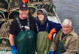 Jenn Michael Lewis, centre, poses with father Scott, left, and grandfather Danny, right, on their deep-sea lobster boat near St. Peters Bay, P.E.I. Danny Lewis has been fishing lobster for over 60 years.