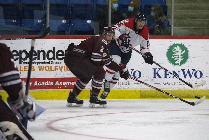 Acadia Axemen forward Cole Rafuse, right, fires a pass across the ice while being defended by Saint Mary’s Huskies blue-liner Walter Flower Oct. 27 at the Andrew H. McCain Arena in Wolfville.