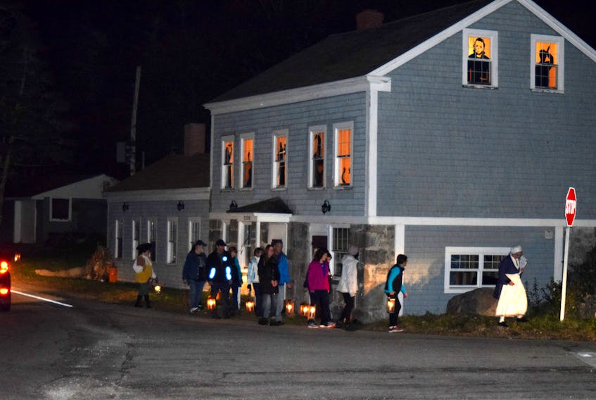 Participants in one of the walking lantern tours of the historic district in Barrington, walk past the Homer house, which has been decked out for Halloween.  KATHY JOHNSON