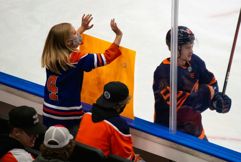 An Edmonton Oilers fan cheers as Kailer Yamamoto (56) warms up against the Philadelphia Flyers at Rogers Place in Edmonton on Wednesday, Oct. 27, 2021.