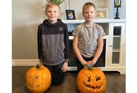 Owen (left) and Joe Diamond pose with a couple of pumpkins, one of many gifts that have been dropped at their doorstep because the family will have to stay in isolation over Halloween.