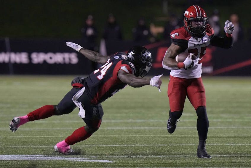  Calgary Stampeders running back Ka’Deem Carey evades a tackle by Ottawa Redblacks linebacker Micah Awe as he runs with the ball at TD Place Stadium in Ottawa on Friday, Oct. 29, 2021.