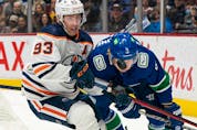 Edmonton Oilers' Ryan Nugent-Hopkins (left) and Vancouver Canucks' Jack Rathbone battle for the puck during first period NHL hockey action in Vancouver on Saturday, Oct. 30, 2021. 