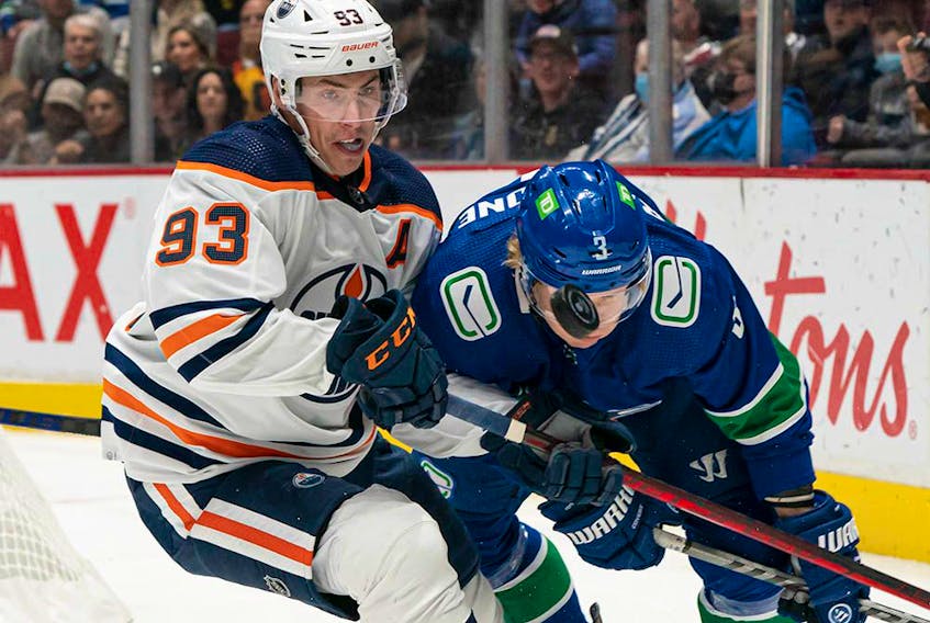 Edmonton Oilers' Ryan Nugent-Hopkins (left) and Vancouver Canucks' Jack Rathbone battle for the puck during first period NHL hockey action in Vancouver on Saturday, Oct. 30, 2021. 