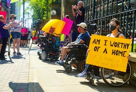 April Hubbard holds a sign as she attends a Disability Rights Coalition rally outside Province House on Friday, Aug. 13, 2021.