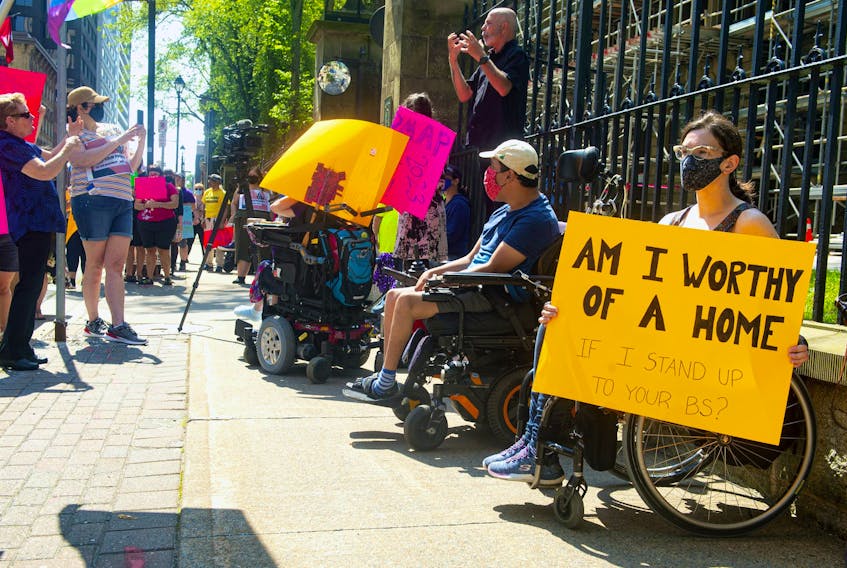 April Hubbard holds a sign as she attends a Disability Rights Coalition rally outside Province House on Friday, Aug. 13, 2021.