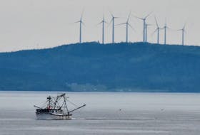 A fishing vessel sails by with wind turbines in Digby County in the background. A wind farm is being proposed for Sandy Point, Shelburne County. TINA COMEAU • TRICOUNTY VANGUARD