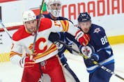  Calgary Flames forward Milan Lucic causes havoc in front of Winnipeg Jets goaltender Connor Hellebuyck with Nate Schmidt defending at Canada Life Centre in Winnipeg on Wednesday, Oct. 6, 2021.