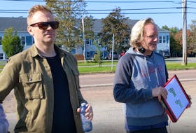 Nathan Macintosh, at left, standing with Jonathan Torrens while he debriefs the crew during a set change outside the Valley Variety store.
