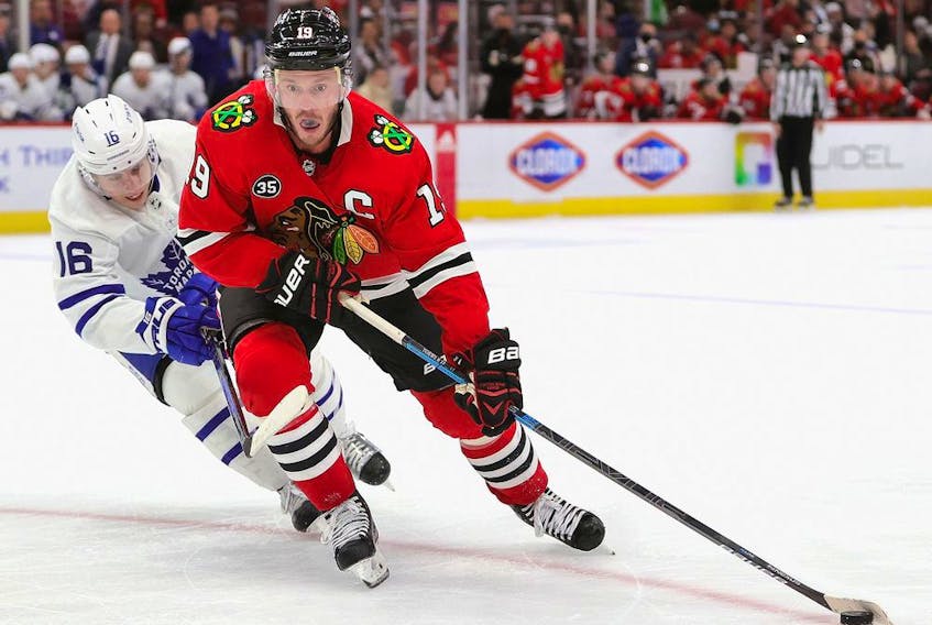 Jonathan Toews #19 of the Chicago Blackhawks turns with the puck under pressure from Mitchell Marner #16 of the Toronto Maple Leafs at the United Center on October 27, 2021 in Chicago, Illinois.