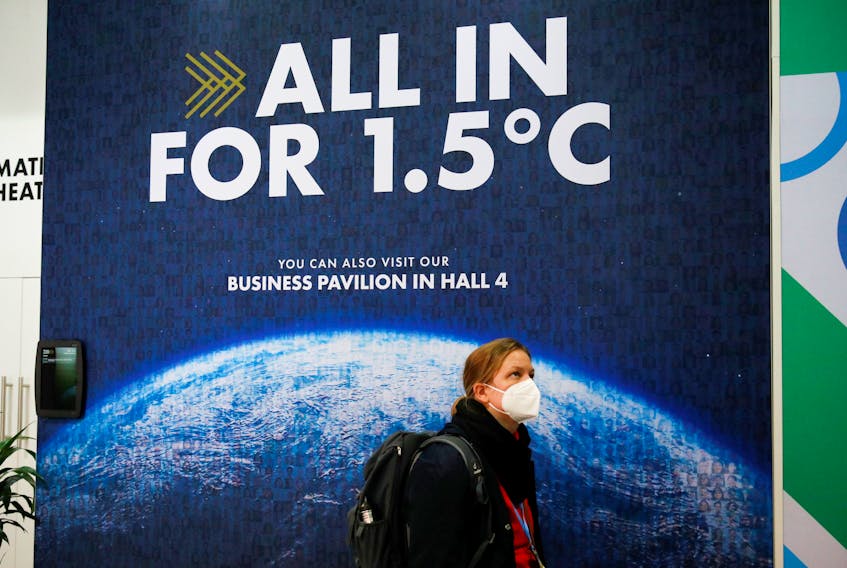 A delegate walks past a climate change poster at the UN Climate Change Conference (COP26) in Glasgow, Scotland on Nov. 1, 2021.