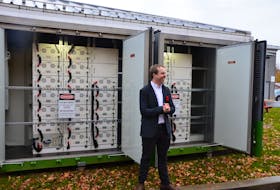 StorTera electrical engineer Scott Ledinghan with the commercial-scale StorHub battery system that has been installed at Berwick town hall. KIRK STARRATT