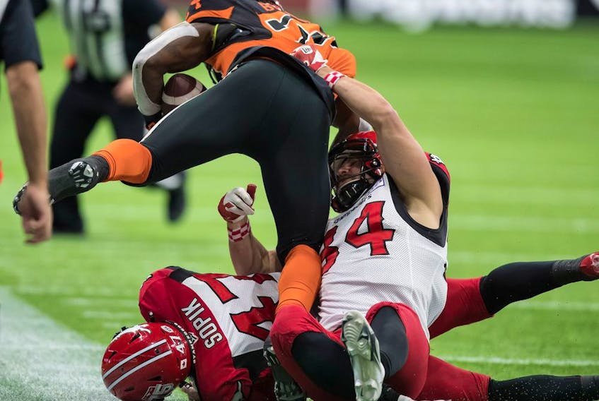 BC Lions' James Butler, (front left) is tackled by Calgary Stampeders' Ante Milanovic-Litre (34) and Fraser Sopik (47) during the first half of a CFL football game in Vancouver, on Friday, November 12, 2021.