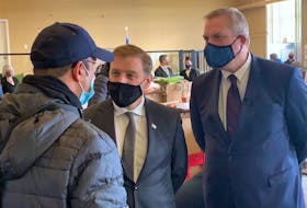 Premier Andrew Furey (centre) and Minister of Immigration, Population Growth and Skills Gerry Byrne (right) speak with an Afghan man who recently arrived with his family in Newfoundland and Labrador from the NATO base in Kosovo.
