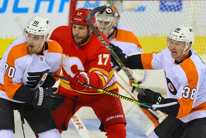 The Calgary Flames' Milan Lucic battles the Philadelphia Flyers' Rasmus Ristolainen and Patrick Brown at the Scotiabank Saddledome in Calgary on Saturday, Oct. 30, 2021.