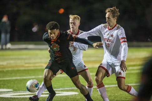Kairo Coore of the Cape Breton Capers, middle, fends off a pair of Laval Rouge et Or during U Sports Men’s Soccer Championship quarterfinal action at Ravens’ Perch Field in Ottawa on Thursday. Cape Breton won the game 3-2 in overtime. PHOTO CONTRIBUTED/CARLETON UNIVERSITY ATHLETICS.
