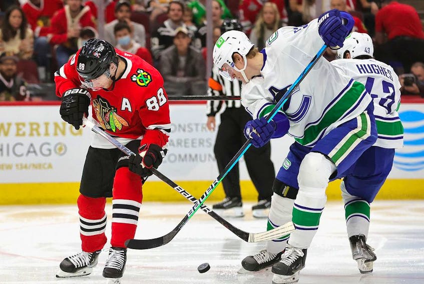 Patrick Kane, left, of the Chicago Blackhawks and Tyler Myers of the Vancouver Canucks battle for the puck at the United Center on Oct. 21 in Chicago.