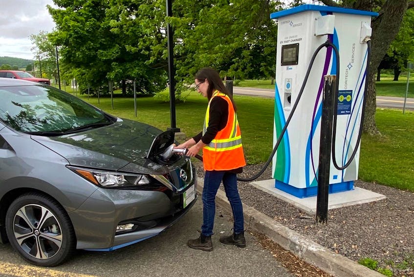 A person plugs an electric vehicle into a bidirectional charger at the NSCC Middleton campus. - NSCC