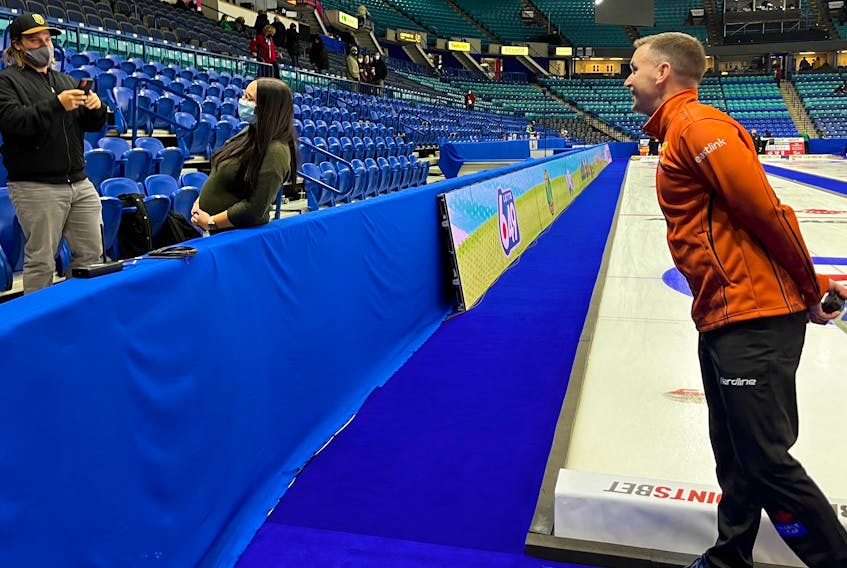 Brad Gushue maintains an appropriate social distance while posing for a photo with a fan at the Tim Hortons Trials, the Canadian curling Olympic qualifying event in Saskatoon. Gushue and his St. John's rink are 3-0 through the first three days of the competition. — Curling Canada photo/Michael Burns