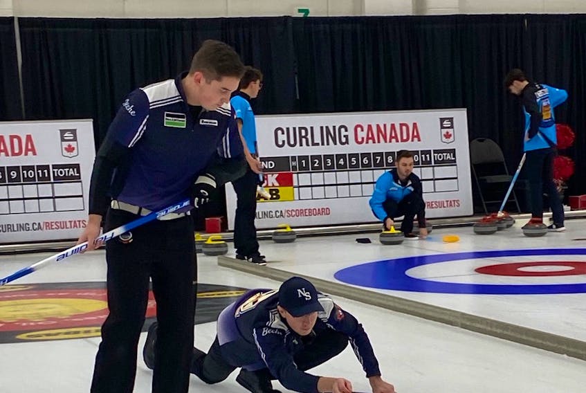Nova Scotia third Joel Krats releases the rock as lead Scott Weagle prepares to sweep during action at the New Holland world junior curling qualifier in Saskatoon on Tuesday. The Owen Purcell-skipped rink defeated Quebec in the tournament opener. – Darlene Danyliw / Curling Canada