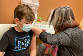 Newfoundland and Labrador's chief medical officer of health Dr. Janice Fitzgerald administers the COVID-19 vaccine to nine-year-old Charlie Gover at a clinic in St. John's Thursday, Nov. 25.