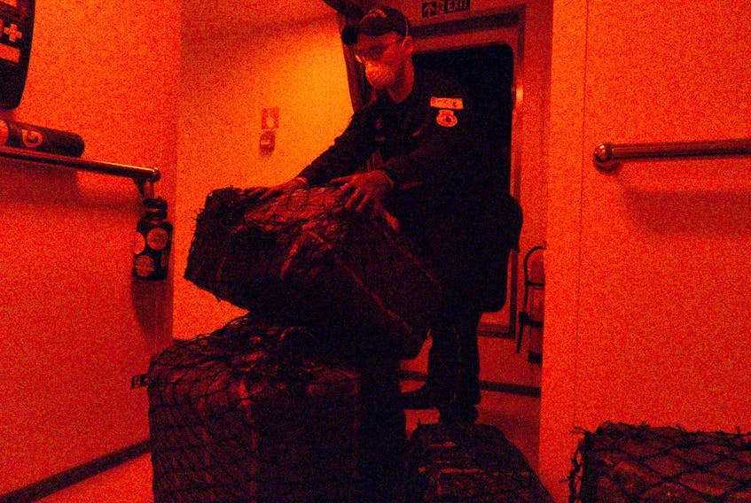 A sailor from HMCS Harry DeWolf totes a bail of cocaine seized from smugglers.