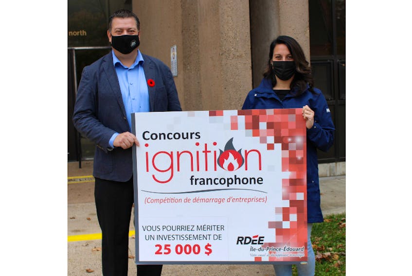 Economic Growth Minister Matthew MacKay and co-ordinator of the Francophone Ignition Contest pose with the $25,000 sponsorship to be awarded to the contest winner.
