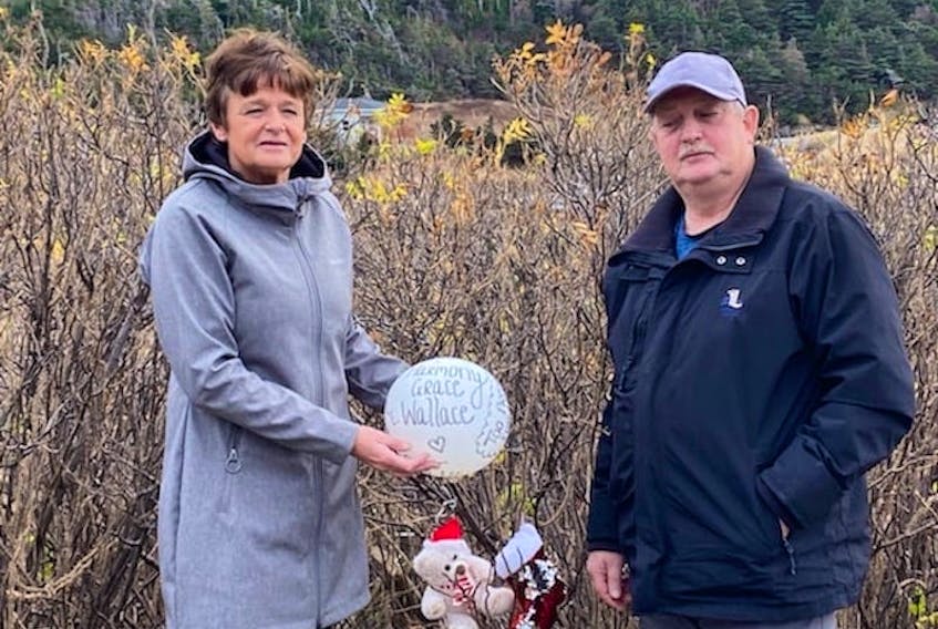 Jenny Best-Power and Peter Power pose on the road to Gooseberry Cove where they found the memorial balloon for Harmony Grace Wallace. They placed a teddy bear and Christmas stocking in the bushes to mark the spot.