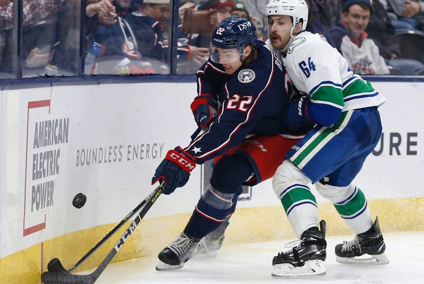 CP-Web. Columbus Blue Jackets' Jake Bean, left, tries to clear the puck as Vancouver Canucks' Tyler Motte defends during the third period of an NHL hockey game Friday, Nov. 26, 2021, in Columbus, Ohio.