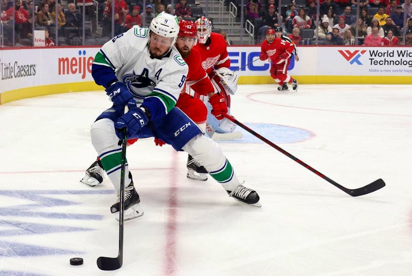 J.T. Miller, foreground, of the Vancouver Canucks battles for the puck against Filip Hronek of the Red Wings at Little Caesars Arena on Oct. 16 in Detroit.