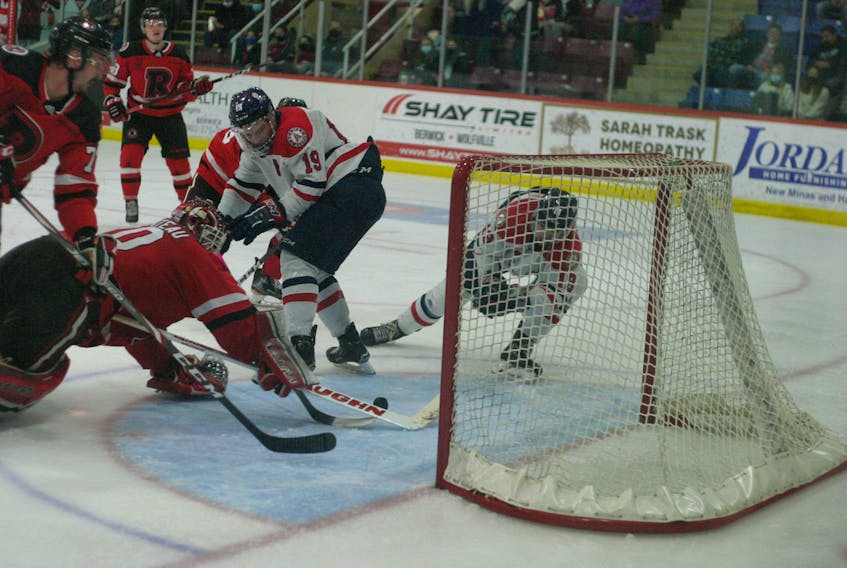 Acadia Axemen forward Eric Henderson, right, swats at the puck as UNB Reds goalie Rylan Parenteau dives back to unsuccessful to try and stop it from crossing the goal-line Nov. 26 during Atlantic University Sport hockey action in Wolfville.