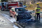A St. John's firefighter hoses down a vehicle that caught on fire following a three-vehicle collision on Elizabeth Avenue Monday afternoon.