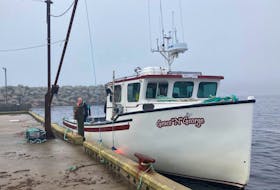 Adam Sam waits on the Grace 'n' George fishing boat for passengers to transport between Neils Harbour and Ingonish on Nov. 26, the first day water transport started to help residents who are stranded due to road washout caused by last weeks torrential rainstorm. NICOLE SULLIVAN/CAPE BRETON POST 