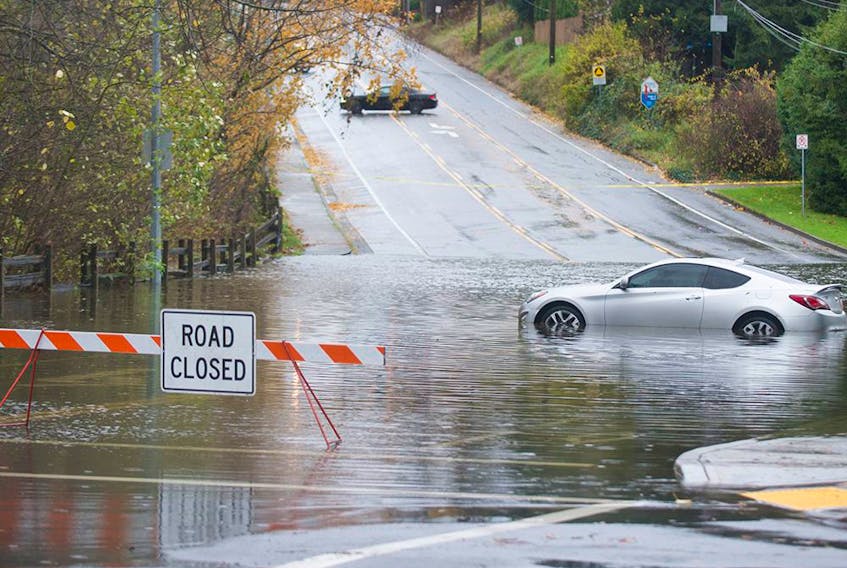 A car sits in a pool of water in the closed intersection of Old Yale Road and Mitchell Street in Abbotsford on Nov. 15, 2021. Two days of rains have flooded, closed or washed out many roads in the Lower Mainland and the Fraser Valley.