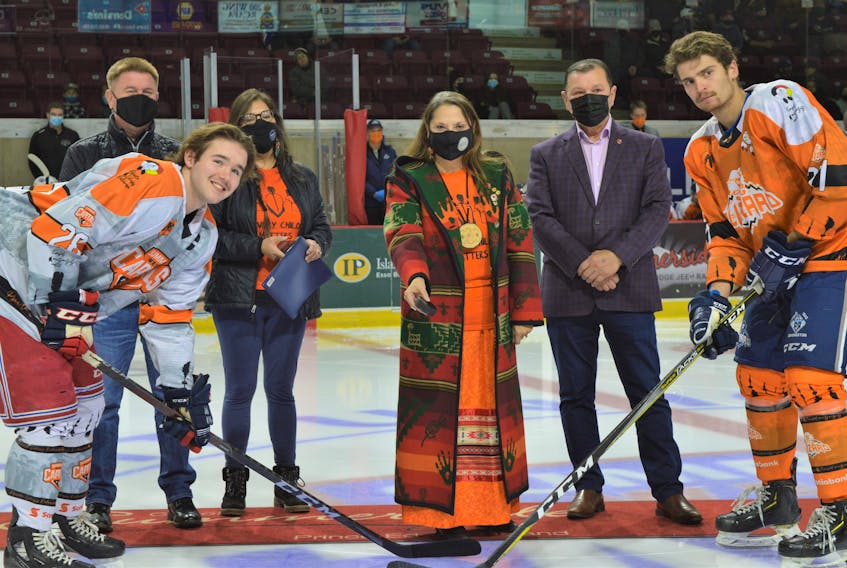 Lennox Island First Nation Chief Darlene Bernard, flanked by Maritime Junior Hockey League president Steve Dykeman, left, Lennox Island First Nation Coun. Madeline Sark and P.E.I. Sen. Brian Francis, drops the puck for the ceremonial face-off between Summerside D. Alex MacDonald Ford Western Capitals captain Josh MacDonald and Edmundston Blizzard defenceman Brendan Sibley. Both the Caps and the Blizzard players wore specially designed jerseys during the Saturday, Nov. 27 game to raise awareness about Indigenous Reconciliation following the discovery of unmarked graves at residential school sites in Canada. 

