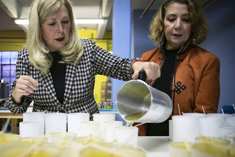 Riau Canada director of operations Louise Bourassa, left, pours hot candle wax into a mold while president and founder Franca Ciambella looks on at their Montreal plant on Thursday Nov. 18, 2021.